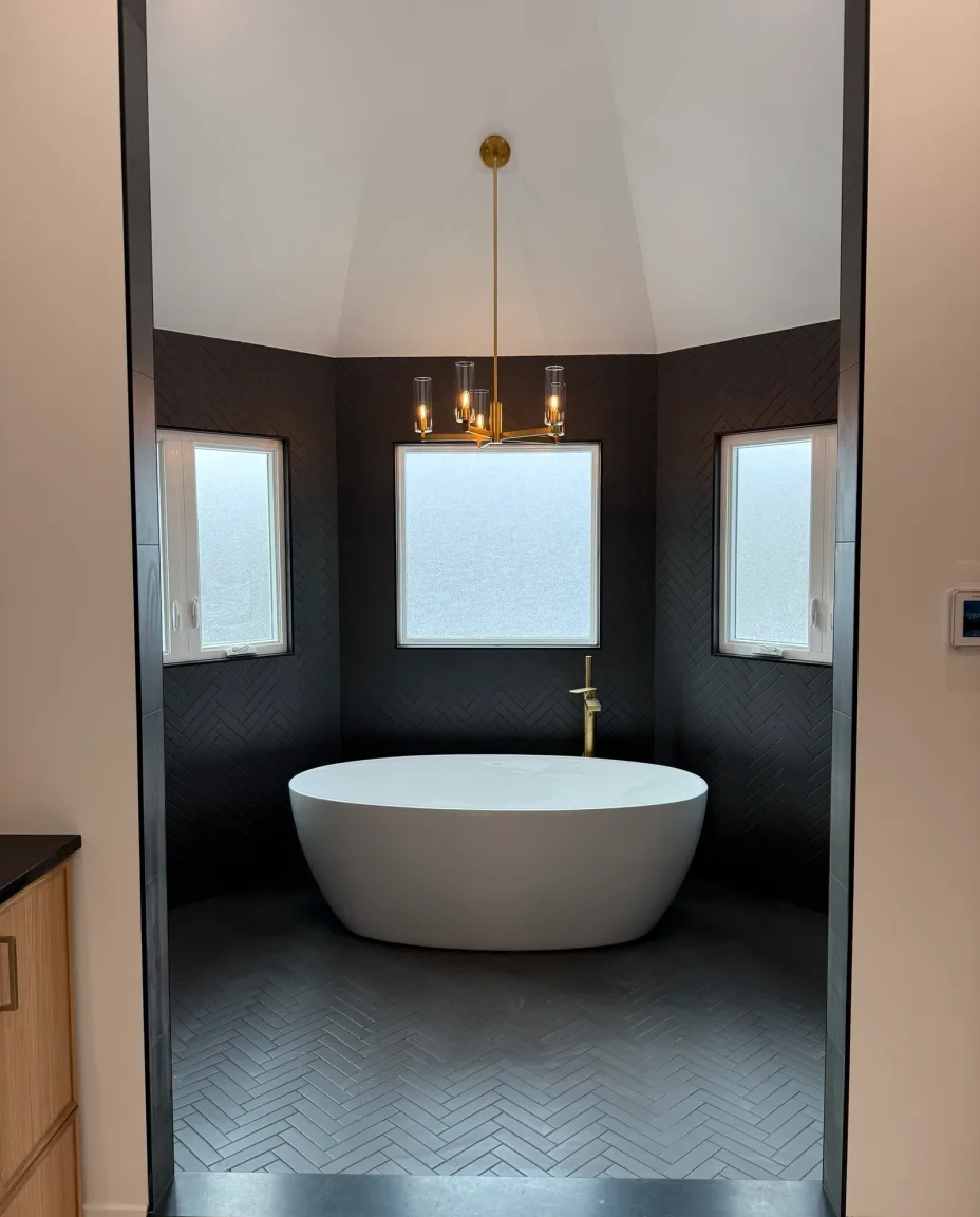 Spa-style primary bathroom in marble and brass with natural light