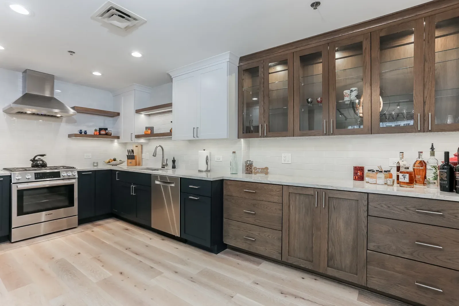 Condo renovation in Chicago, IL - two-tone kitchen with glass-front upper cabinets by Luxe Development